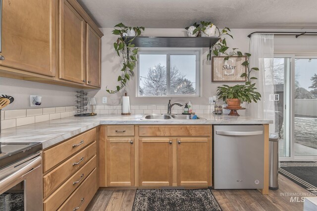 kitchen with a textured ceiling, sink, stainless steel appliances, and light hardwood / wood-style flooring