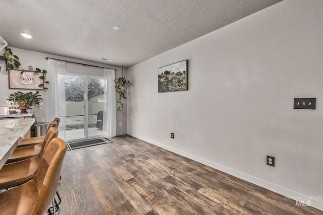 unfurnished dining area with wood-type flooring and a textured ceiling