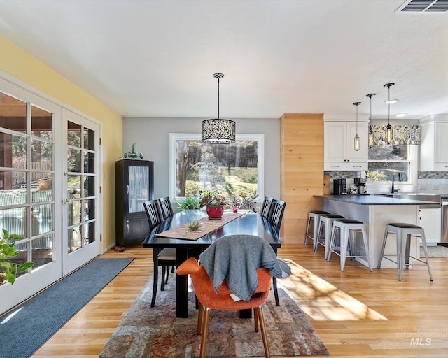 dining space featuring light wood-style floors, visible vents, and french doors