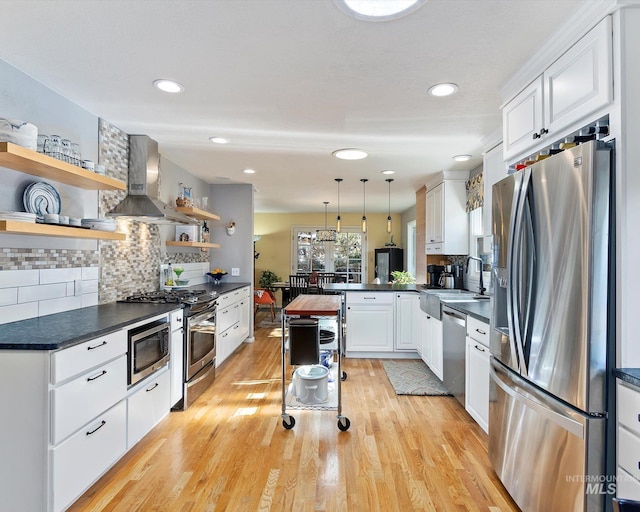 kitchen with dark countertops, wall chimney range hood, appliances with stainless steel finishes, and open shelves