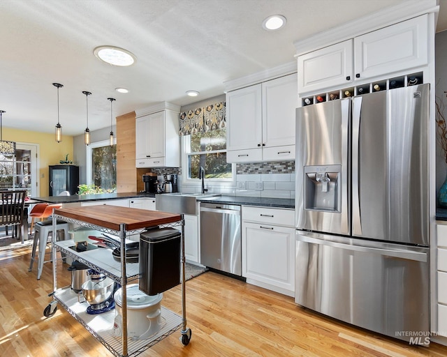 kitchen featuring stainless steel appliances, light wood finished floors, white cabinetry, and decorative backsplash