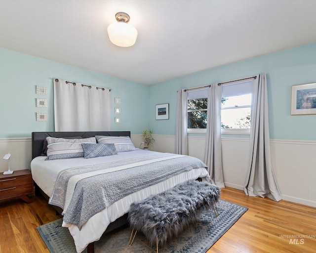 bedroom featuring a wainscoted wall and light wood finished floors