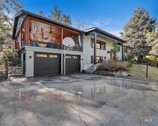 view of front of home with driveway, a balcony, an attached garage, and ceiling fan