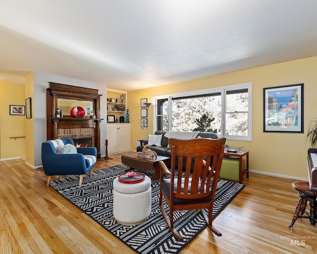 living area with a fireplace, light wood-style flooring, and baseboards