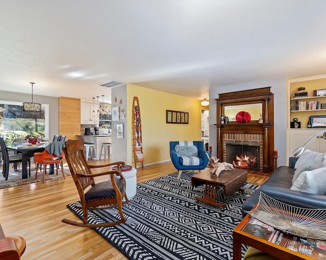 living area with baseboards, a fireplace, visible vents, and light wood-style floors