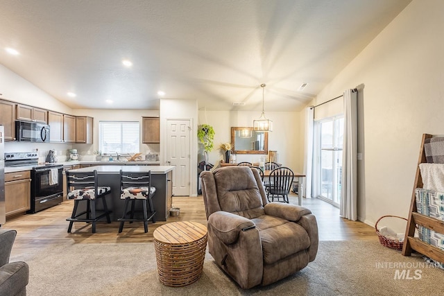 living area featuring vaulted ceiling, a notable chandelier, light wood-style flooring, and recessed lighting