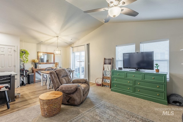 living room featuring vaulted ceiling, a ceiling fan, and light wood finished floors