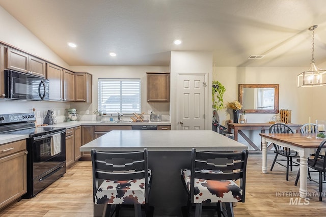kitchen featuring a kitchen island, light wood-style flooring, a sink, and black appliances