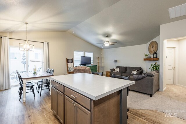 kitchen with light countertops, visible vents, lofted ceiling, ceiling fan with notable chandelier, and hanging light fixtures
