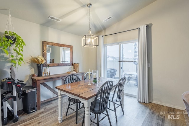dining area with visible vents, an inviting chandelier, wood finished floors, and vaulted ceiling