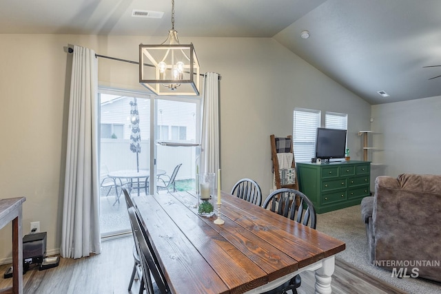 dining room with a healthy amount of sunlight, visible vents, vaulted ceiling, and a chandelier