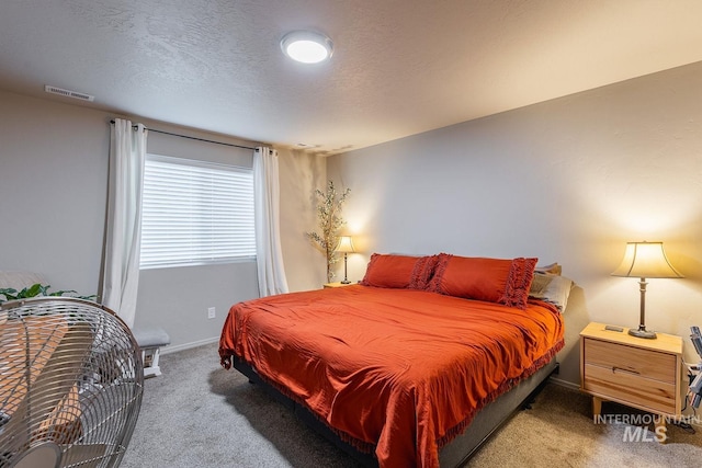 bedroom featuring baseboards, a textured ceiling, visible vents, and light carpet