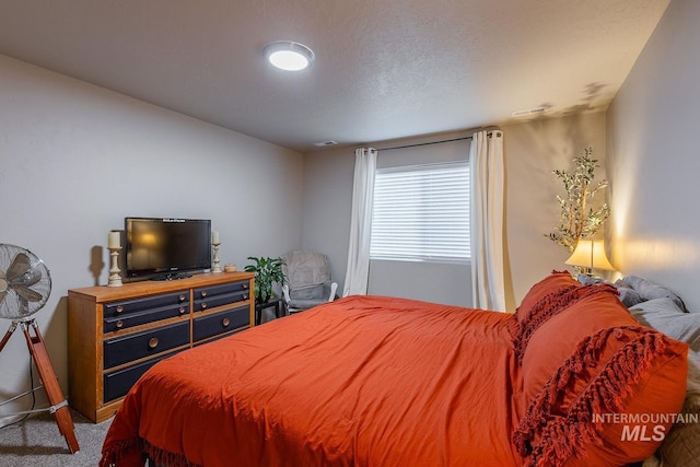 carpeted bedroom featuring a textured ceiling and visible vents