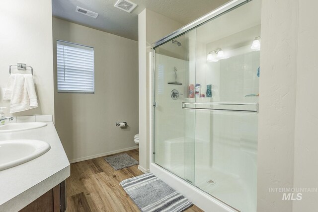 bathroom featuring a shower stall, visible vents, wood finished floors, and a sink