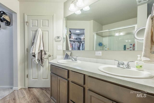 full bathroom featuring wood finished floors, a sink, a walk in closet, and a shower stall