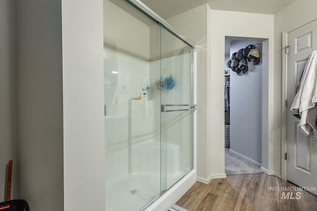 bathroom featuring a stall shower, baseboards, and wood finished floors