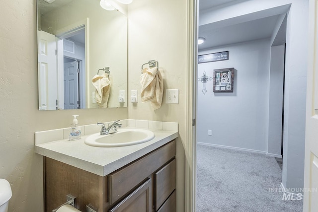 bathroom featuring toilet, vanity, and baseboards