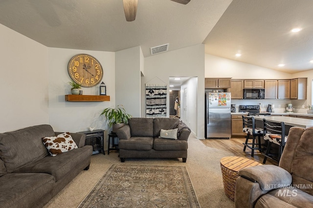 living area featuring a textured ceiling, visible vents, vaulted ceiling, and a ceiling fan