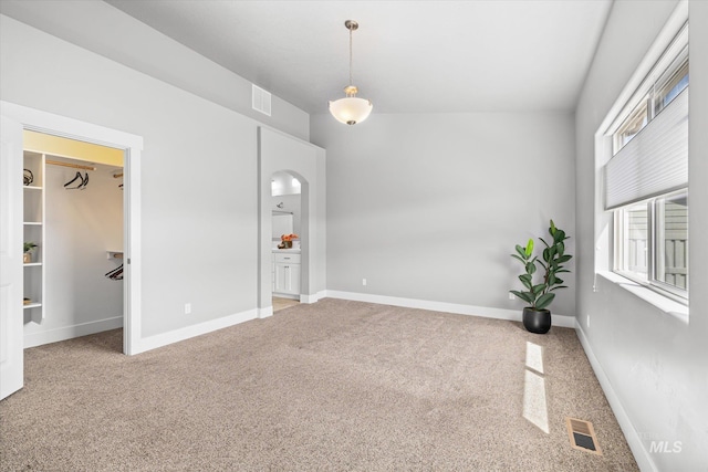 carpeted spare room with baseboards and arched walkways