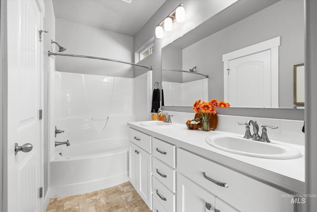 full bath featuring stone finish floors, double vanity, and shower / washtub combination