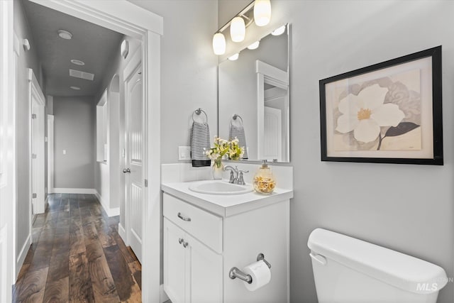 bathroom with wood finished floors, toilet, vanity, and baseboards