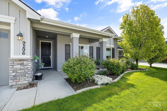 property entrance with a lawn and stone siding