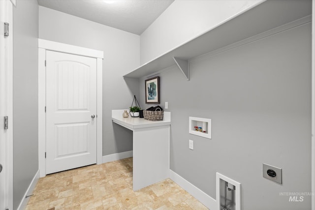 clothes washing area with electric dryer hookup, hookup for a washing machine, baseboards, and stone finish flooring