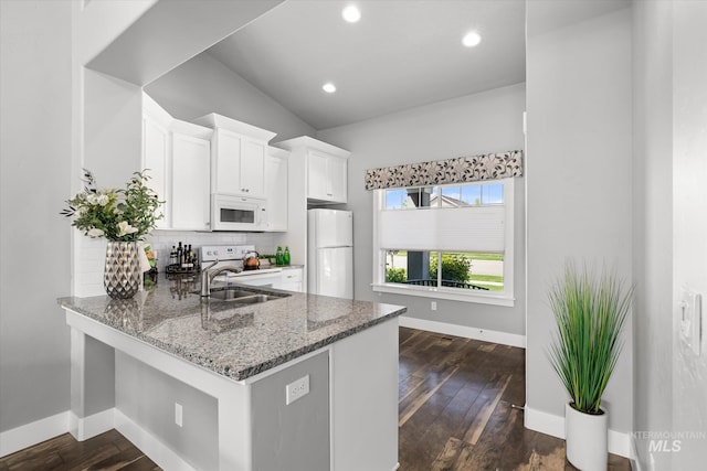kitchen featuring white appliances, a sink, stone counters, baseboards, and decorative backsplash
