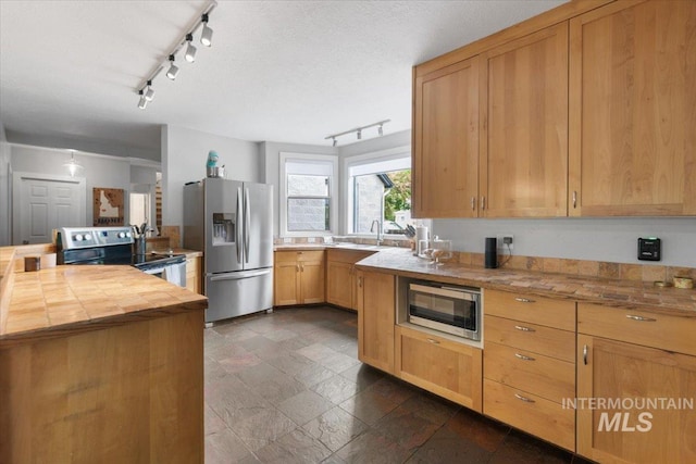 kitchen featuring stainless steel appliances, light brown cabinetry, and butcher block counters