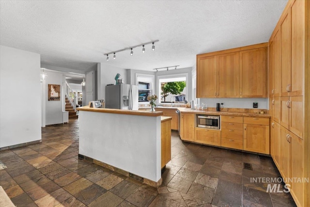 kitchen with stainless steel appliances, track lighting, and a textured ceiling