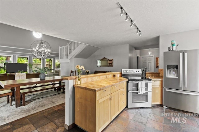 kitchen featuring appliances with stainless steel finishes, light brown cabinetry, wooden counters, a chandelier, and a textured ceiling