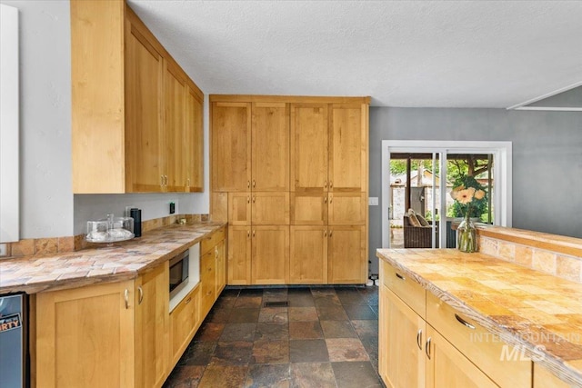 kitchen featuring built in microwave, dishwashing machine, butcher block countertops, and a textured ceiling