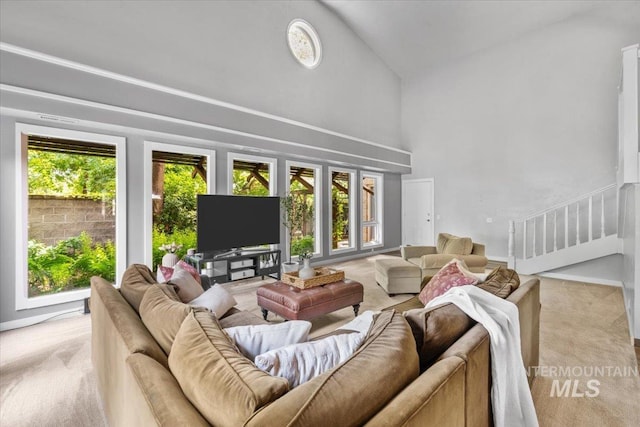 carpeted living room with a healthy amount of sunlight and high vaulted ceiling