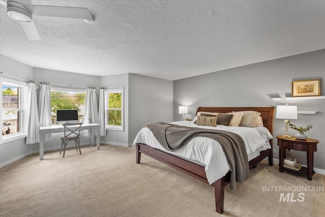 bedroom with ceiling fan, light colored carpet, and a textured ceiling