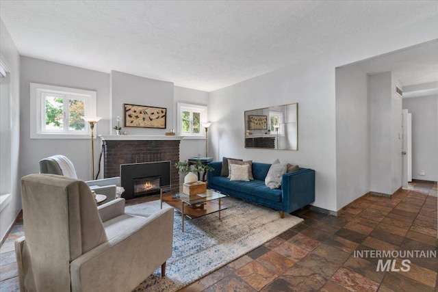 living room featuring plenty of natural light, a brick fireplace, and a textured ceiling