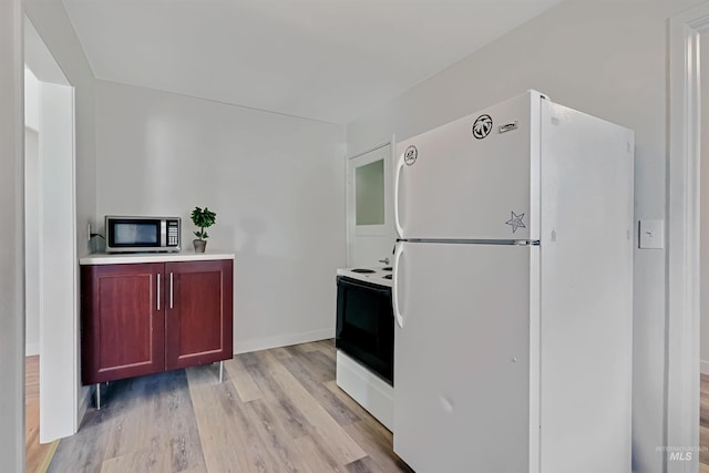 116 6th Ave E, Jerome, ID 83338 - kitchen with stainless steel microwave, freestanding refrigerator, electric range oven, light wood finished floors, and reddish brown cabinets