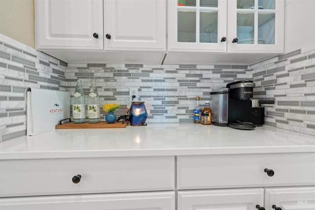 interior space with glass insert cabinets, white cabinetry, decorative backsplash, and light countertops