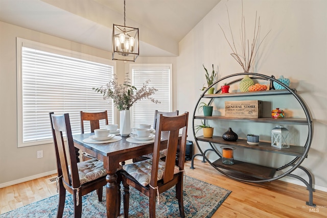 dining room featuring lofted ceiling, a notable chandelier, baseboards, and wood finished floors