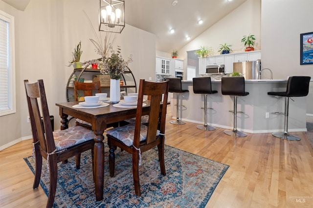 dining space with high vaulted ceiling, light wood-type flooring, and baseboards