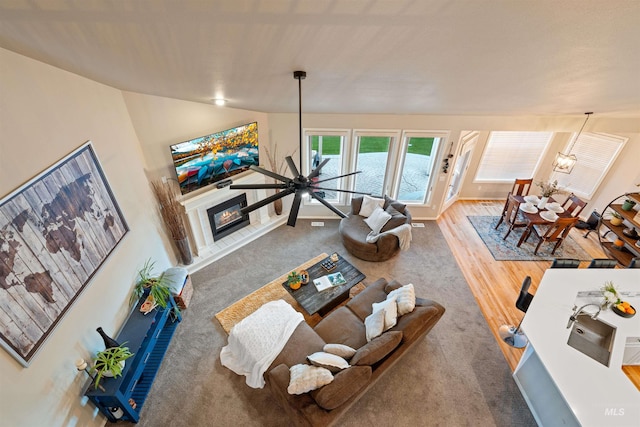 living area featuring lofted ceiling, an inviting chandelier, and a glass covered fireplace