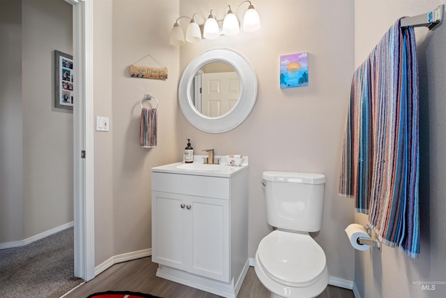 bathroom featuring baseboards, vanity, toilet, and wood finished floors