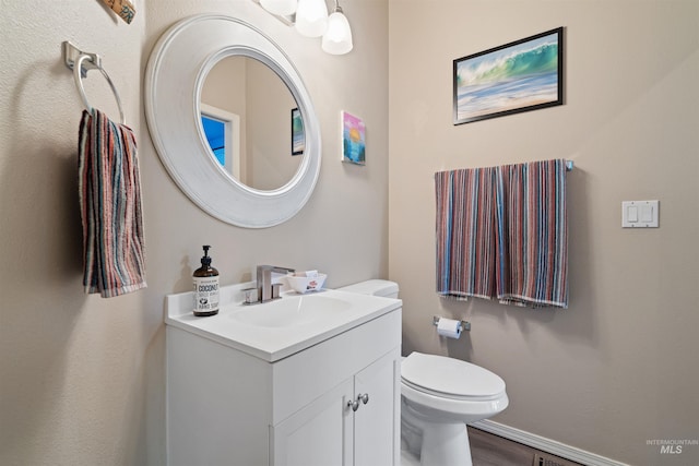 half bathroom with baseboards, vanity, toilet, and wood finished floors