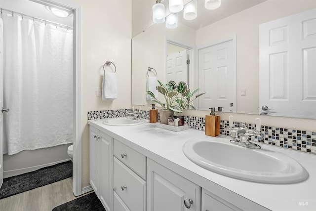 bathroom featuring wood finished floors, a sink, toilet, and double vanity