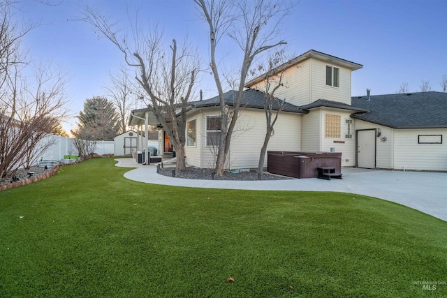 rear view of house featuring an outdoor structure, fence, a yard, a shed, and a hot tub