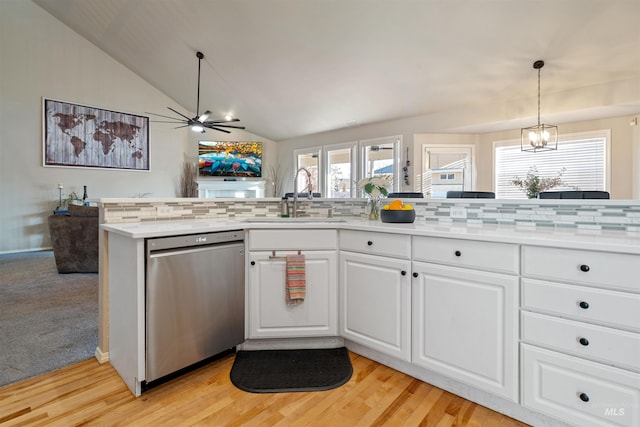 kitchen featuring decorative backsplash, lofted ceiling, light countertops, stainless steel dishwasher, and a sink