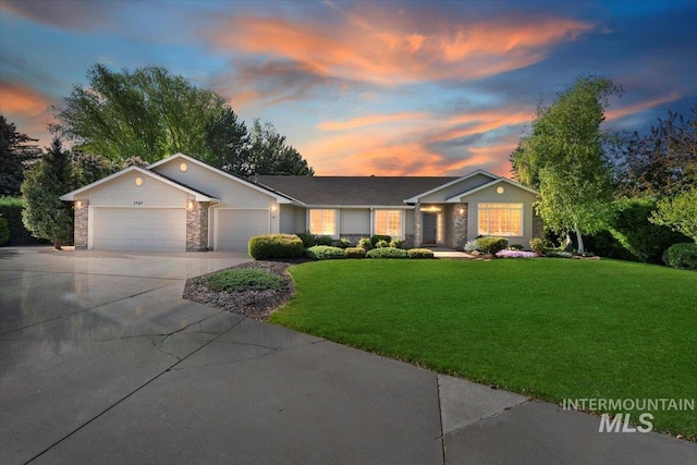 ranch-style home with an attached garage, concrete driveway, a front lawn, and stone siding
