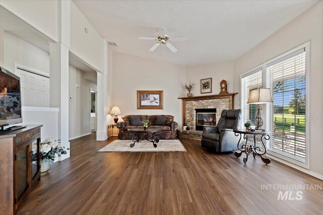 living room with a brick fireplace, ceiling fan, dark wood-style floors, and baseboards