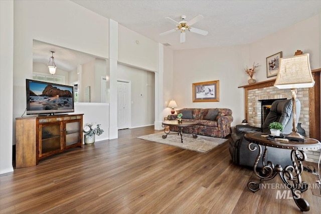 living room with wood finished floors, a fireplace, and ceiling fan