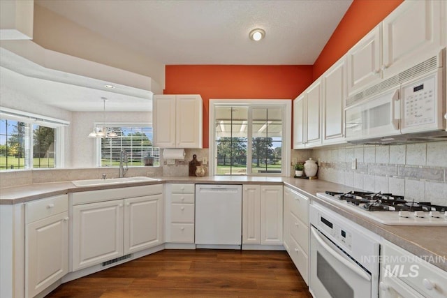 kitchen featuring white appliances, a sink, backsplash, and a chandelier