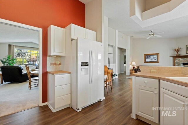 kitchen with white fridge with ice dispenser, dark wood-style flooring, open floor plan, and white cabinets